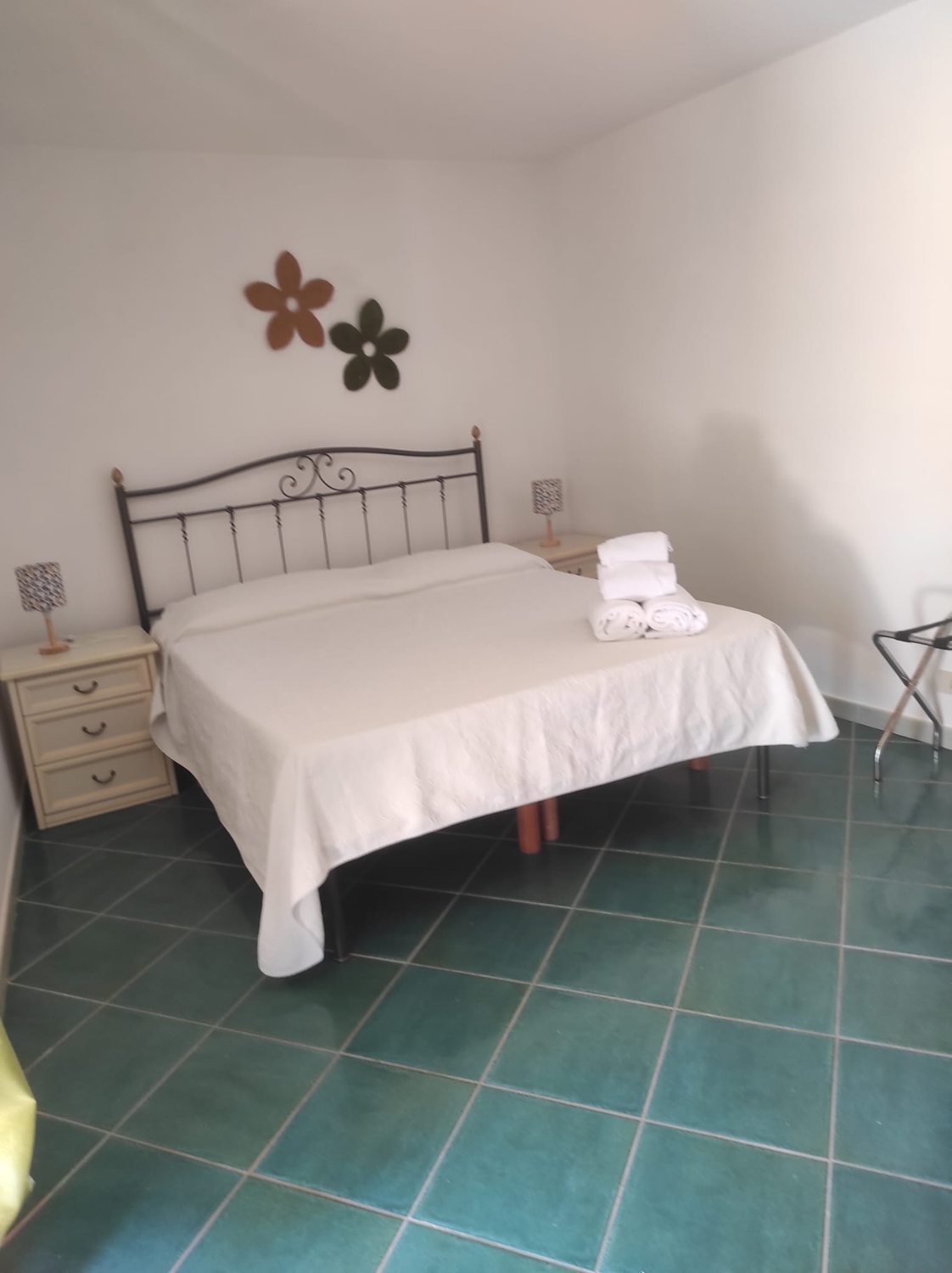 Camera con letto in ferro e pavimento in cotto verde